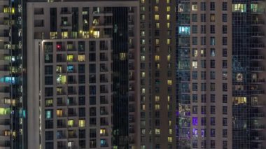 Çok katlı binanın içinde aydınlatma ve apartmanlarda zaman atlamalı insanları hareket ettiren pencereler.