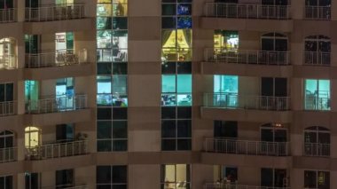 Çok katlı binanın içinde aydınlatma ve apartmanlarda zaman atlamalı insanları hareket ettiren pencereler.