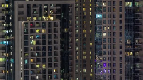 Ramen van het gebouw met meerdere verdiepingen met verlichting binnen en bewegende mensen in appartementen timelapse. — Stockvideo
