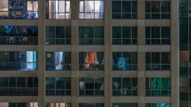 Fönstren i flera våningar byggnad med belysning inuti och flytta människor i lägenheter Timelapse. — Stockvideo