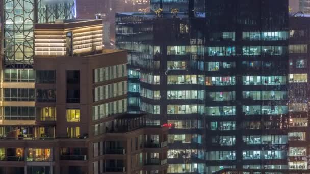 Lights in windows of modern multiple story office building in urban setting at night timelapse — Stock Video