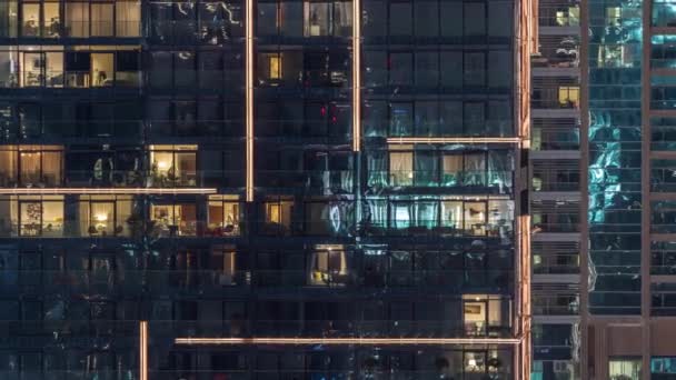Вогні у вікнах сучасної багатоповерхової будівлі в міському середовищі в нічний час — стокове відео