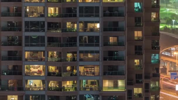 Lights in windows of modern multiple story building in urban setting at night timelapse — Stock Video