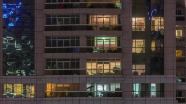 Dış apartman zaman atlamalı gece görünümü. Pencerelerde yanıp sönen ışıklar ile yüksek katlı gökdelen