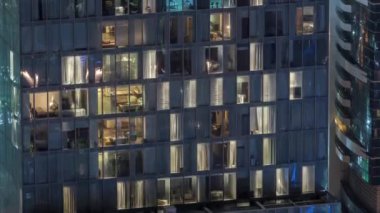 Dış apartman kulesinin gece görüşü. Pencerelerinde yanıp sönen ışıklar olan yüksek gökdelen