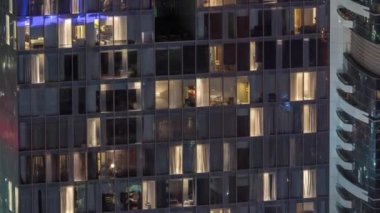 Dış apartman kulesinin gece görüşü. Pencerelerinde yanıp sönen ışıklar olan yüksek gökdelen