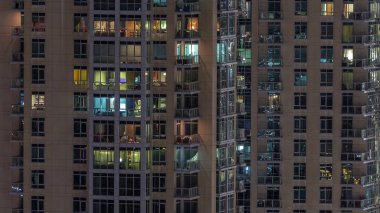 Çok katlı binanın içinde aydınlatma ve apartmanlarda zaman atlamalı insanları hareket ettiren pencereler.