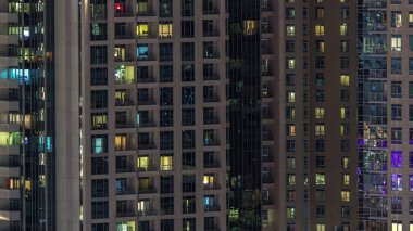 Çok katlı binanın içinde aydınlatma ve apartmanlarda zaman atlamalı insanları hareket ettiren pencereler.