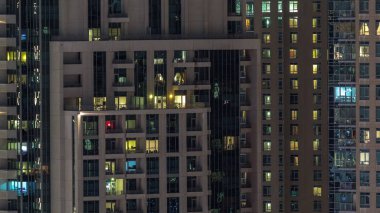 Çok katlı binanın içinde aydınlatma ve apartmanlarda zaman atlamalı insanları hareket ettiren pencereler.