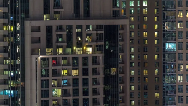 Okna wielokondygnacyjnego budynku z oświetleniem wewnątrz i poruszających się osób w apartamentach timelapse. — Zdjęcie stockowe