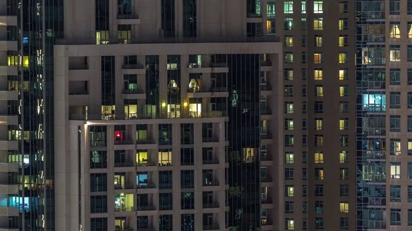 Çok katlı binanın içinde aydınlatma ve apartmanlarda zaman atlamalı insanları hareket ettiren pencereler. — Stok fotoğraf