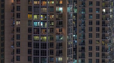 Çok katlı binanın içinde aydınlatma ve apartmanlarda zaman atlamalı insanları hareket ettiren pencereler.