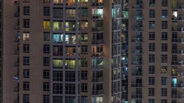 Çok katlı binanın içinde aydınlatma ve apartmanlarda zaman atlamalı insanları hareket ettiren pencereler.