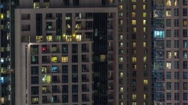 Çok katlı binanın içinde aydınlatma ve apartmanlarda zaman atlamalı insanları hareket ettiren pencereler.