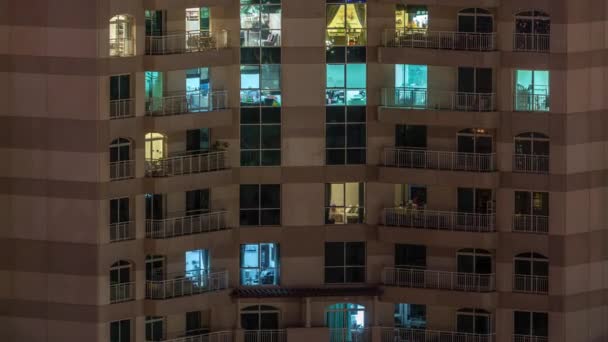 Okna vícepodlažní budovy s osvětlením uvnitř a přesunem osob v apartmánech.