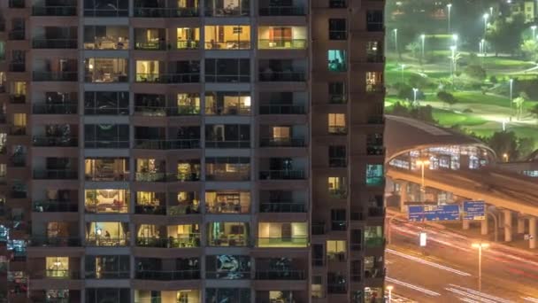 Luces en las ventanas del moderno edificio de varios pisos en el entorno urbano en la noche timelapse — Vídeo de stock