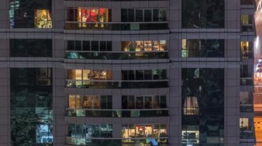 Dış apartman zaman atlamalı gece görünümü. Pencerelerde yanıp sönen ışıklar ile yüksek katlı gökdelen