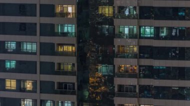 Dış apartman zaman atlamalı gece görünümü. Pencerelerde yanıp sönen ışıklar ile yüksek katlı gökdelen