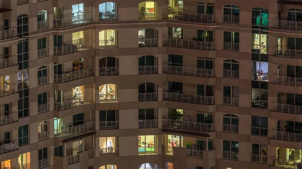 Ramen van het gebouw met meerdere verdiepingen met verlichting binnen en bewegende mensen in appartementen timelapse. — Stockfoto