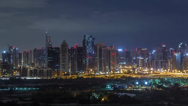 Wieże Jumeirah Lake i Dubai Marina wieżowce i pole golfowe podczas wszystkich nocnych timelapse, Dubaj, Zjednoczone Emiraty Arabskie — Zdjęcie stockowe
