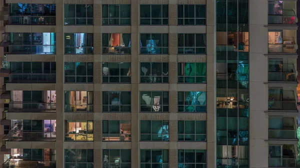 Ventanas del edificio de varios pisos con iluminación interior y personas en movimiento en apartamentos timelapse . —  Fotos de Stock