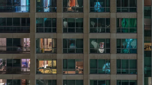 Ramen van het gebouw met meerdere verdiepingen met verlichting binnen en bewegende mensen in appartementen timelapse. — Stockfoto