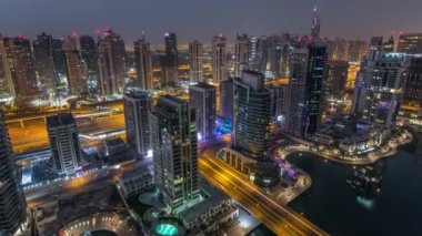 Dubai Marina gece gündüz timelapse havadan üst görünümü. Modern kuleler ve yolda trafik