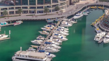 Dubai marina timelapse yüzen yatlar üzerinde havadan görünümü. Beyaz tekneler yeşil kanal suyunda.