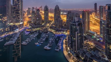 Dubai Marina gece gündüz timelapse havadan üst görünümü. Modern kuleler ve yolda trafik