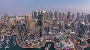 Dubai Marina'nın havadan üstten gündüz gece ye doğru görünümü. Modern kuleler ve yolda trafik