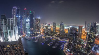 Dubai Marina gece timelapse havadan üst görünümü. Modern kuleler ve yolda trafik