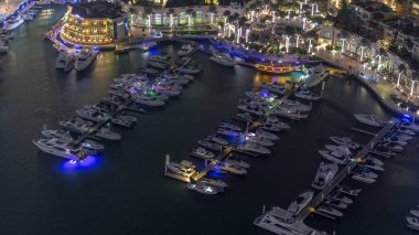 Dubai marina gece zaman atlamalı yüzen yatlar havadan görünümü. Beyaz tekneler kanal suyunda.