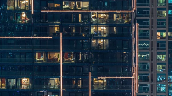 Lights in windows of modern multiple story building in urban setting at night timelapse — Stock Photo, Image