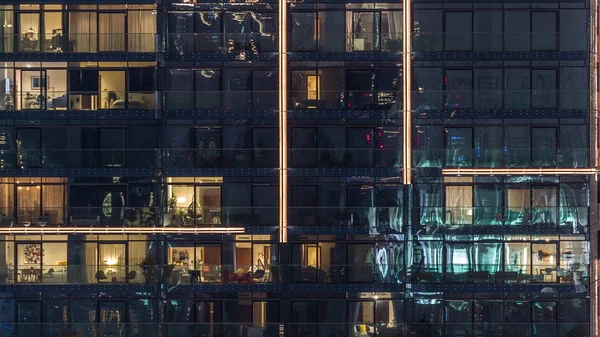 Valot ikkunat modernin monikerroksinen rakennus kaupunkiympäristössä yöllä timelapse — kuvapankkivalokuva