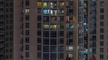 Çok katlı binanın içinde aydınlatma ve apartmanlarda zaman atlamalı insanları hareket ettiren pencereler.