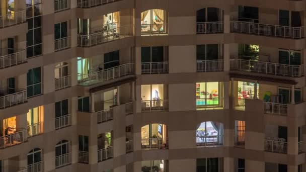 Fönstren i flera våningar byggnad med belysning inuti och flytta människor i lägenheter Timelapse. — Stockvideo