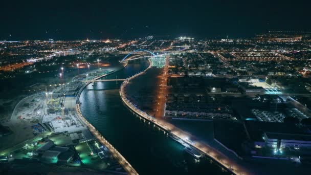 Dubai water canal with footbridge aerial night view from Downtown skyscrapers rooftop — ストック動画