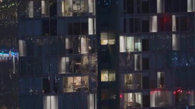 Dış apartman kulesinin gece görüşü. Pencerelerinde yanıp sönen ışıklar olan yüksek gökdelen