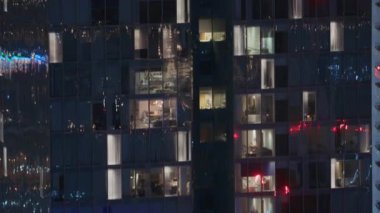 Dış apartman kulesinin gece görüşü. Pencerelerinde yanıp sönen ışıklar olan yüksek gökdelen