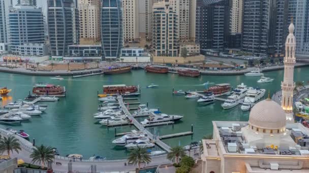 Σκάφη στη Μαρίνα Ντουμπάι πλαισιωμένα από το Τζαμί Αλ Ραχίμ και οικιστικούς πύργους και ουρανοξύστες εναέρια μέρα με τη νύχτα timelapse. — Αρχείο Βίντεο