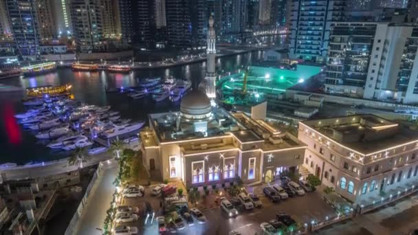 Σκάφη στη Μαρίνα Ντουμπάι πλαισιωμένα από το Τζαμί Αλ Ραχίμ και οικιστικούς πύργους και ουρανοξύστες εναέρια νύχτα timelapse. — Αρχείο Βίντεο