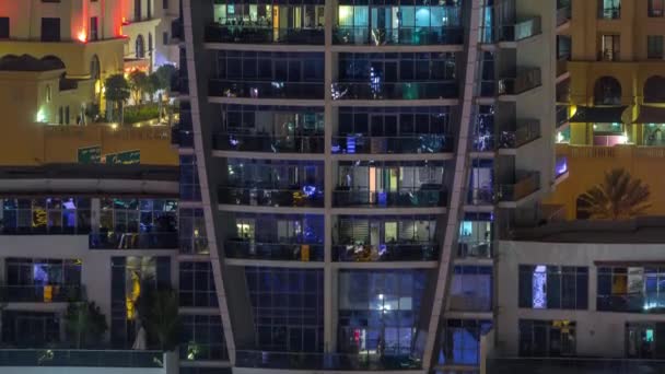 Filas de ventanas brillantes con gente en el edificio de apartamentos por la noche . — Vídeos de Stock