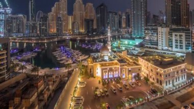 Dubai Marina 'daki yatlar El-Rahim Camii' nin ve konut kulelerinin ve gökdelenlerin yan tarafındaki yatlar gece gündüz gökdelenler.