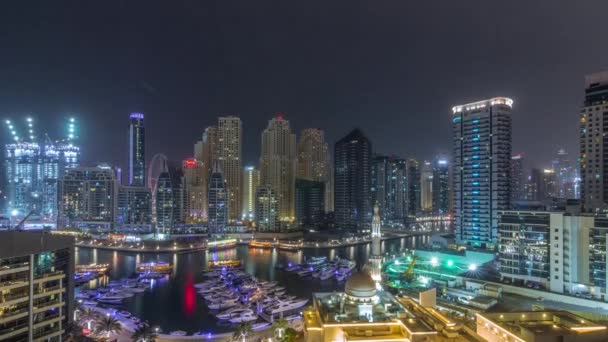 Yachts in Dubai Marina flanked by the Al Rahim Mosque and residential towers and skyscrapers aerial night timelapse. — Stock Video