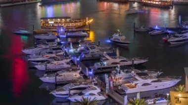 Dubai Marina körfezindeki iskeleye park etmiş lüks yatlar. Şehir hava manzaralı gece manzaralı.