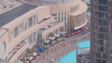 Şehir merkezindeki Dubai 'de fıskiyelerin ve alışveriş merkezlerinin yanında yürüyen bir sürü turist var.