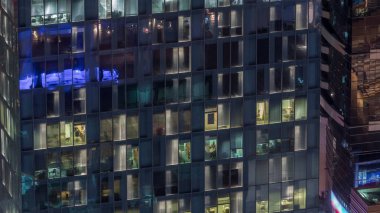 Dış apartman kulesinin gece görüşü. Pencerelerinde yanıp sönen ışıklar olan yüksek gökdelen