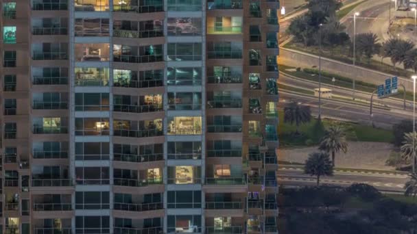 Rijen van gloeiende ramen met mensen in appartementencomplex 's nachts. — Stockvideo