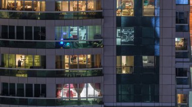 Dış apartman zaman atlamalı gece görünümü. Pencerelerde yanıp sönen ışıklar ile yüksek katlı gökdelen
