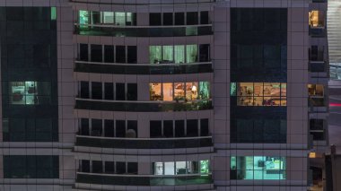 Dış apartman zaman atlamalı gece görünümü. Pencerelerde yanıp sönen ışıklar ile yüksek katlı gökdelen